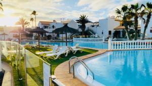 a resort swimming pool with chairs and umbrellas at Happiness in Caleta De Fuste