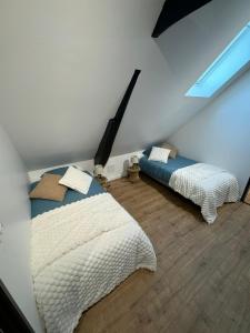 a attic bedroom with two beds and a window at Le cottage champêtre in Escaudoeuvres