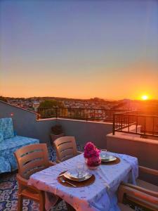 a table and chairs on a balcony with the sunset at The Rooftop Urla in Urla