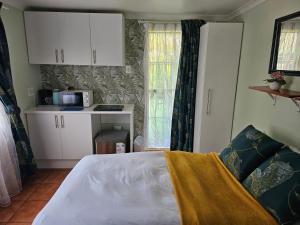 a bedroom with a bed and a kitchen with a microwave at King Sanctuary in Centurion