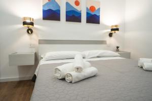 a white bedroom with two towels on a bed at Vela Rossa Deluxe Apartment in Trapani