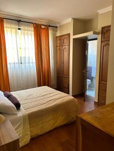 a bedroom with a bed and a door to a bathroom at Amplio y cómodo departamento in Cochabamba