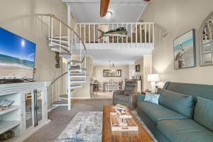a living room with a blue couch and a spiral staircase at Cotton Bayou Unit 8C in Orange Beach
