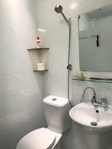 a white bathroom with a toilet and a sink at Timothy House Hue in Hue