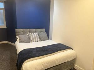 a bed in a room with a blue wall at Liverpool city central 2 bedroom apartment in Liverpool +2 photos