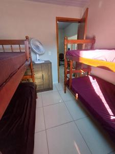 a room with two bunk beds and a fan at Casa da praia dois irmãos in Matinhos