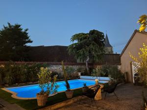a swimming pool in a backyard with chairs and plants at Relais Saint-Jean Levroux in Levroux
