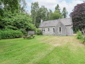 an old stone house with a picnic table in the yard at East Lodge - Crathes Castle in Banchory