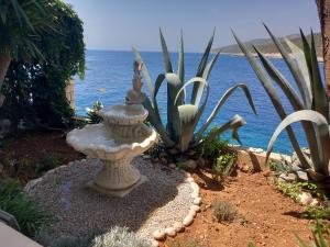 a garden with a statue in front of the ocean at Apartments Ranko in Zavalatica