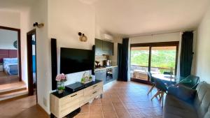 a living room with a flat screen tv and a kitchen at Casa Paradiso in Costa Paradiso