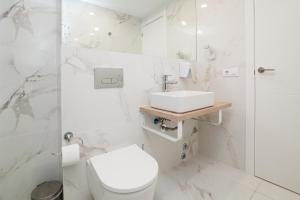 a white bathroom with a toilet and a sink at Ponderosa 611, Las Americas, one bedroom apartment with large terrace and ocean view, next to Siam Park in Playa Fañabe +17 photos