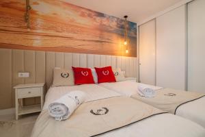 two beds in a bedroom with red pillows on them at Ponderosa 611, Las Americas, one bedroom apartment with large terrace and ocean view, next to Siam Park in Playa Fañabe