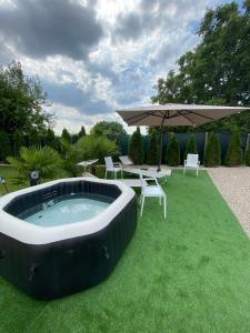 a hot tub in the grass with chairs and an umbrella at AGRITURISMO LE GHIRLANDE in Valeggio sul Mincio
