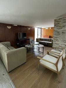 a living room with a couch and a tv at Hotel Tehuelche in Esquel
