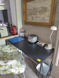 ein schwarzer Schreibtisch mit einem Telefon und einer Lampe in der Unterkunft Rosemary Cottage in Sergines