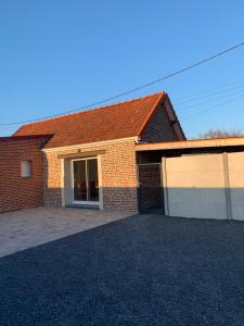 a brick house with a garage with a driveway at Evasion champêtre et moderne in Escaudoeuvres
