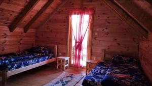 a bedroom with two beds and a window in a log cabin at Eco Village Jasavic in Plav
