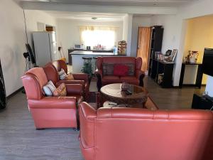a living room with red leather chairs and a table at Ben Kalulu House in Mangeti