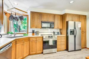 a kitchen with wooden cabinets and a stainless steel refrigerator at Rhododendron Retreat with Hot Tub Steps to River! in Rhododendron