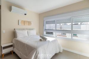 a bedroom with a white bed and a window at Studio encantador e bem localizado PoA-RS VENB504 in Partenon