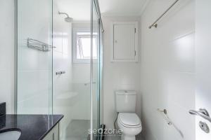 a bathroom with a toilet and a glass shower at Studio encantador e bem localizado PoA-RS VENB504 in Partenon +16 photos