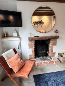 a living room with a fireplace and a mirror at Spring Cottage Bretforton in Bretforton