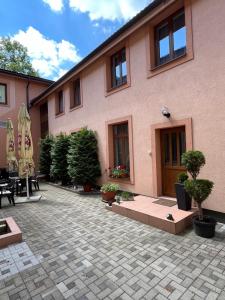 a pink building with a courtyard with potted plants at Garni Hotel Tatramonti in Poprad