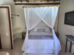 a bedroom with a bed with a mosquito net at Suíte Caju - Conforto e Exclusividade em Trancoso in Trancoso +9 photos