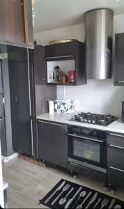 cocina con armarios negros y fogones en Family Home, en Fleury-Mérogis