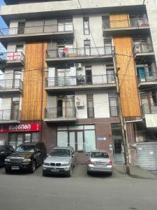 two cars parked in a parking lot in front of a building at Comfy Nook Apartment in Tbilisi City
