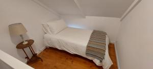 ein kleines weißes Schlafzimmer mit einem Bett und einer Lampe in der Unterkunft Wild Plum Cottage in Kei-mouth Village