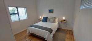 ein kleines Schlafzimmer mit einem Bett mit Fenster in der Unterkunft Wild Plum Cottage in Kei-mouth Village