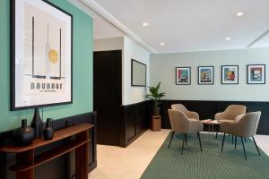 a lobby with chairs and a table and a television at Timhotel Nation in Paris