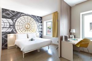 a hotel room with a bed and a desk and a window at B&B Hotel Milano Central Station in Milan