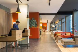 a man standing at a desk in a lobby at B&B Hotel Milano Central Station in Milan