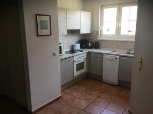 a kitchen with white cabinets and a tile floor at Schöne Wohnung mit Boddenblick in Sagard
