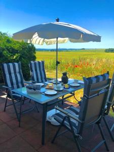 a picnic table with an umbrella and two chairs at Schöne Wohnung mit Boddenblick in Sagard