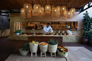 a chef standing behind a counter with baskets of fruit at Insotel Fenicia Prestige Suites & Spa in Santa Eularia des Riu