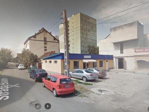 a parking lot with cars parked in front of a building at Riverside White Apartment in Satu Mare