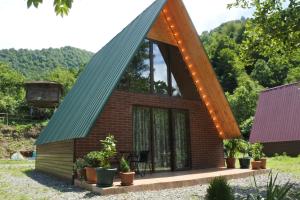 a small house with a pitched roof with lights at Ecohouse Machakhela in Machakhela