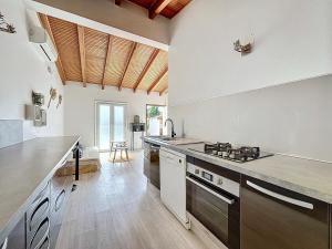 une cuisine avec des murs blancs et un plafond en bois dans l'établissement Petite maison familiale - Très proche de la mer - Les Frères de la Loc', à Pietrosella 25 autres photos