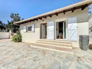 une maison avec des portes blanches et une allée en pierre dans l'établissement Petite maison familiale - Très proche de la mer - Les Frères de la Loc', à Pietrosella