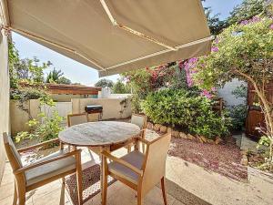 - une table et des chaises sur une terrasse avec un parasol dans l'établissement Petite maison familiale - Très proche de la mer - Les Frères de la Loc', à Pietrosella