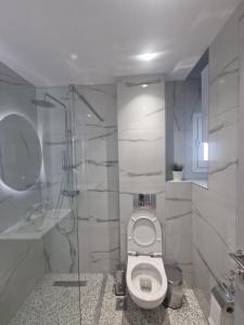 a white bathroom with a toilet and a shower at Cozy Apartment in Asprovalta