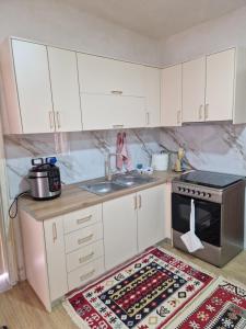 a kitchen with white cabinets and a sink and a rug at Guest House Vajzë S,Kasaj in Vlorë
