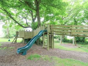 a playground with a slide next to a tree at Stable Cottage in Newport Pembrokeshire