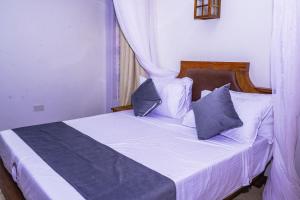 a bedroom with a bed with blue and white pillows at Oasis of Bliss Diani Beach Apartment in Ukunda +11 photos