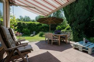 een patio met een parasol en een tafel en stoelen bij Poldersbos 7 - Ouddorp NOT INTENDED FOR COMPANY OR WORK-RELATED STAYS in Ouddorp