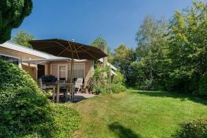 een patio met een tafel en een parasol in een tuin bij Poldersbos 7 - Ouddorp NOT INTENDED FOR COMPANY OR WORK-RELATED STAYS in Ouddorp +72 foto's