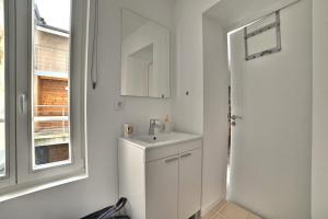 a white bathroom with a sink and a window at Ave César - Confort Moderne, Charme Gallo-Romain, Cœur de Ville, Tv 4K, Fibre in Saintes